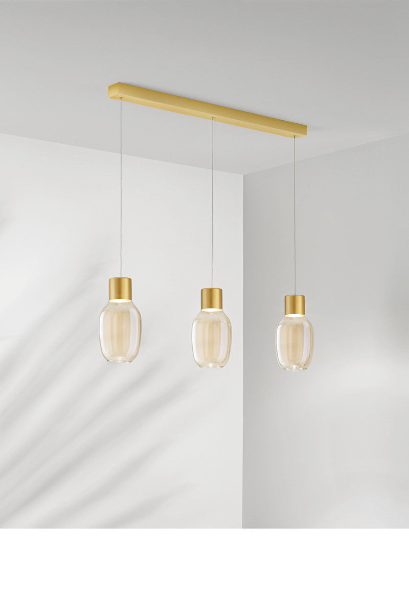 Vue rapprochée du luminaire à trois abat-jours en verre transparent et doré.