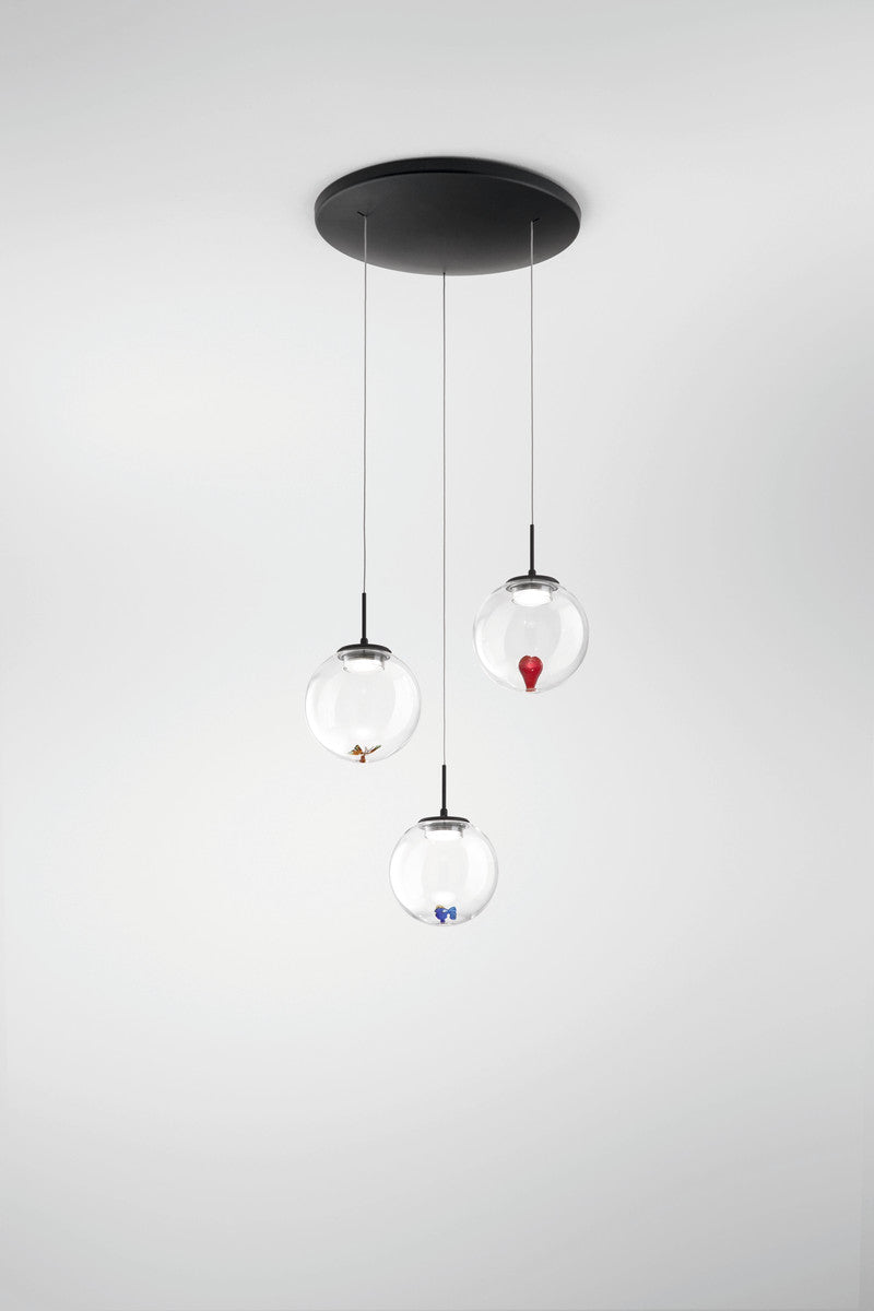 Plan rapproché de la suspension avec ses trois globes transparents et son support noir.