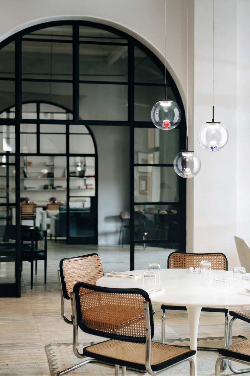 Suspension installée au-dessus d'une table ronde et de chaises cannées dans une salle à manger.