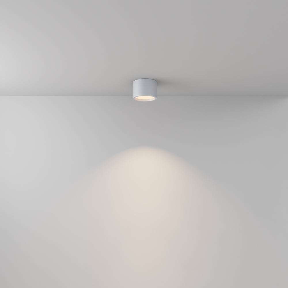 Mise en ambiance d'un plafonnier blanc éclairant un mur minimaliste