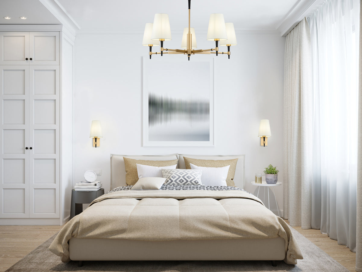Mise en ambiance du plafonnier doré au-dessus d'un lit dans une chambre claire et lumineuse.