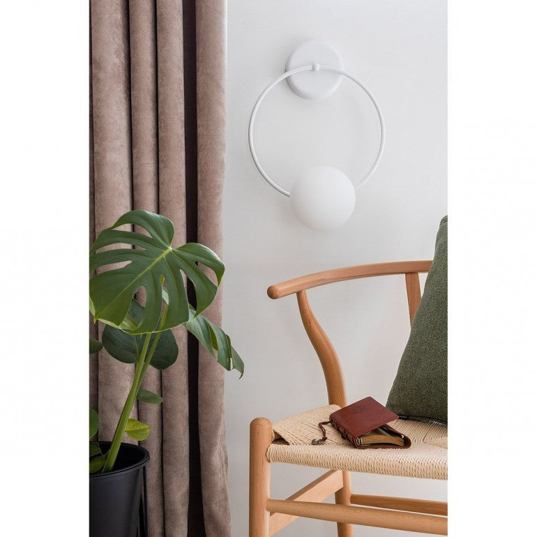 Mise en ambiance salon, applique blanche au mur près d'un rideau et d'une plante