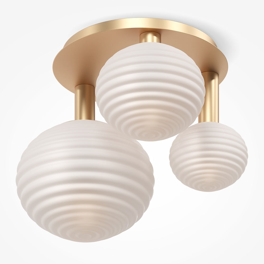 Vue en plongée du plafonnier doré montrant les trois globes en verre strié.