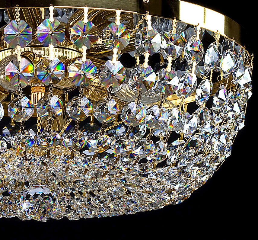 Gros plan sur les pendeloques de cristal taillé et les bobèches dorées du luminaire