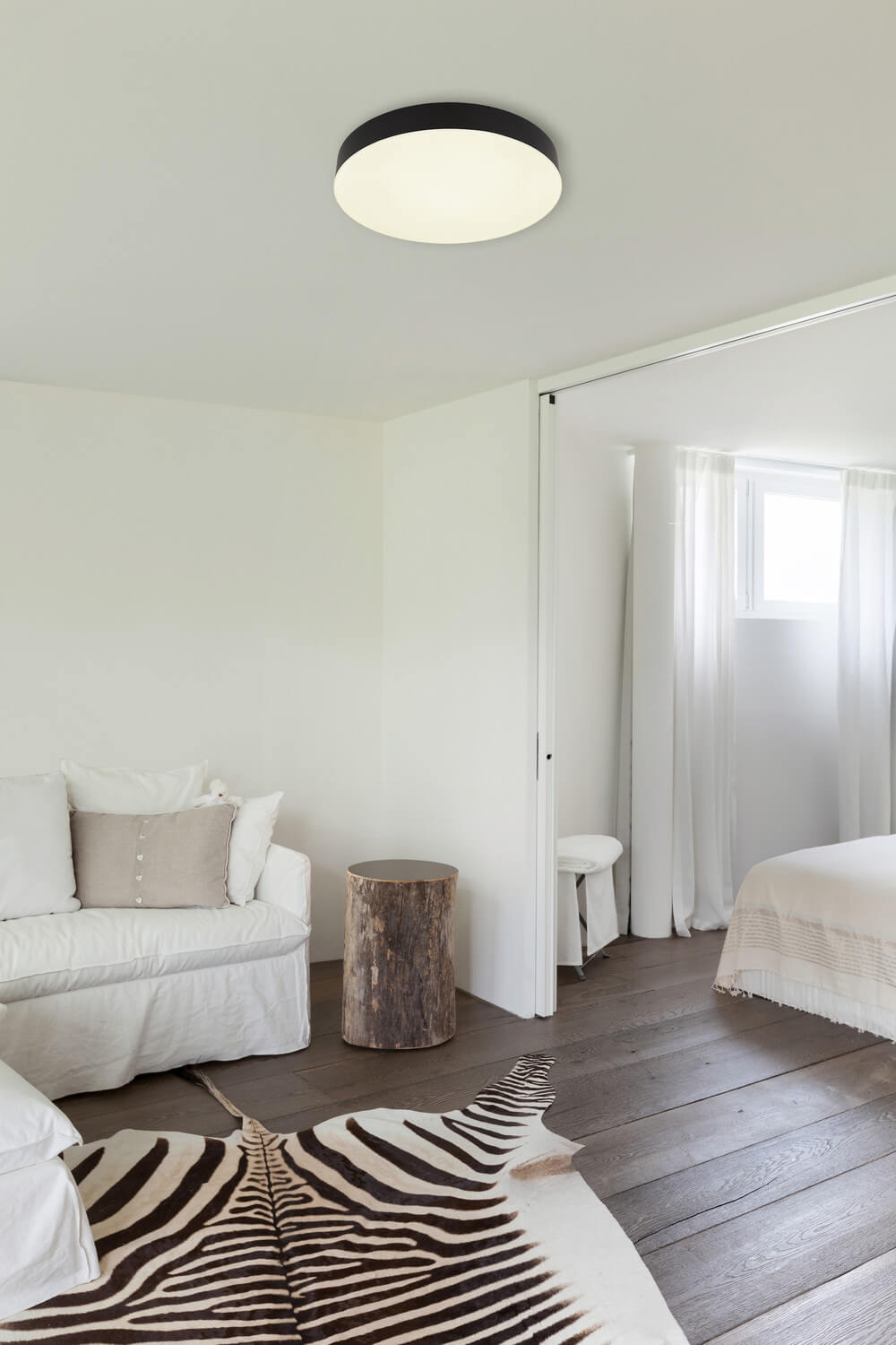 Mise en ambiance : plafonnier allumé au plafond d'une chambre blanche et bois