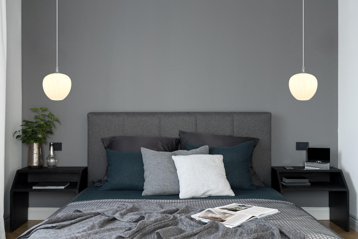 Ambiance de chambre avec deux suspensions blanches allumées de part et d'autre du lit.
