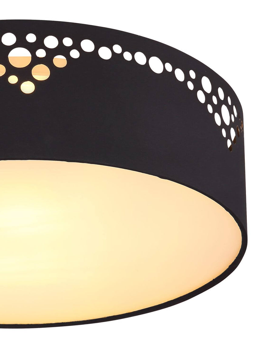 Détail rapproché des perforations rondes laissant passer la lumière chaude du diffuseur