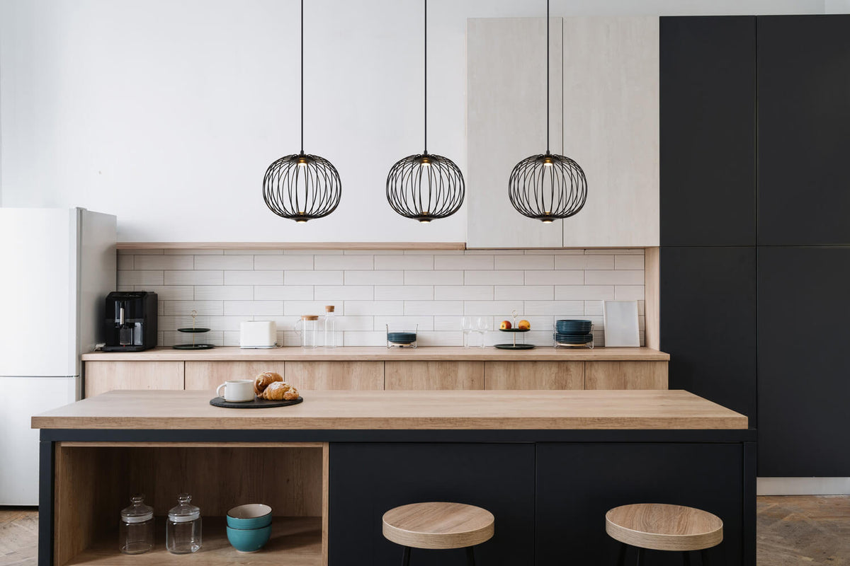 Mise en ambiance d'une cuisine moderne avec trois suspensions noires alignées au-dessus de l'îlot