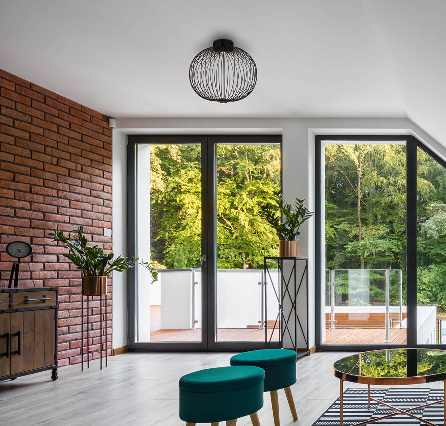 Plafonnier fixé au plafond blanc d'un salon moderne ouvert sur le jardin