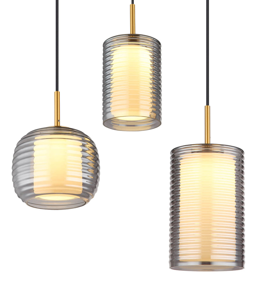 Gros plan sur trois suspensions en verre cannelé, cylindres et boules éclairés de lumière chaude.