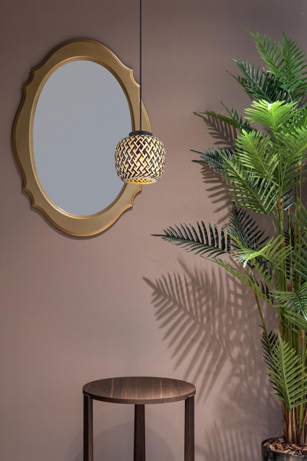 Mise en ambiance du suspension devant un miroir doré et un palmier