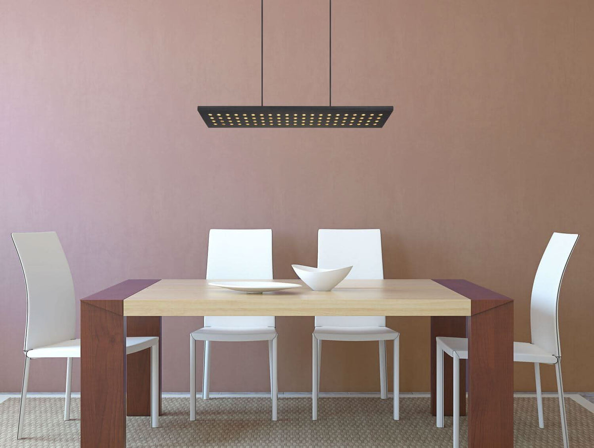 Mise en ambiance du luminaire suspendu au-dessus d'une table à manger dans une pièce rose.