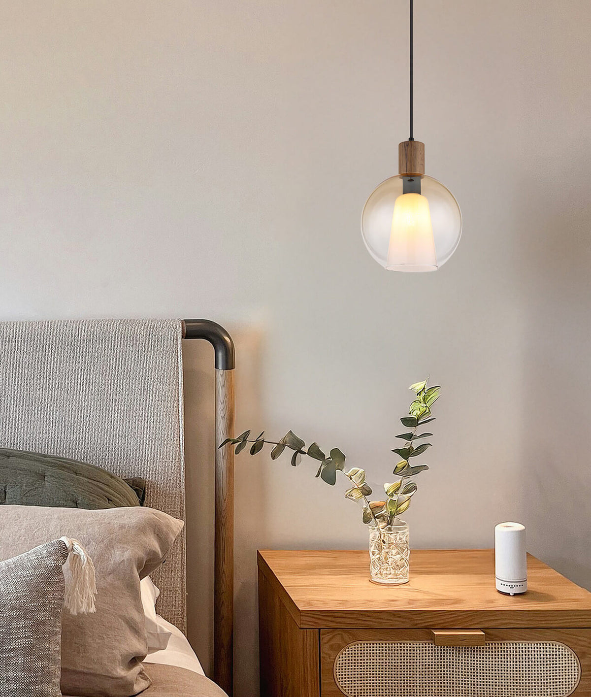 Mise en ambiance du luminaire allumé au-dessus d'une table de chevet en bois.