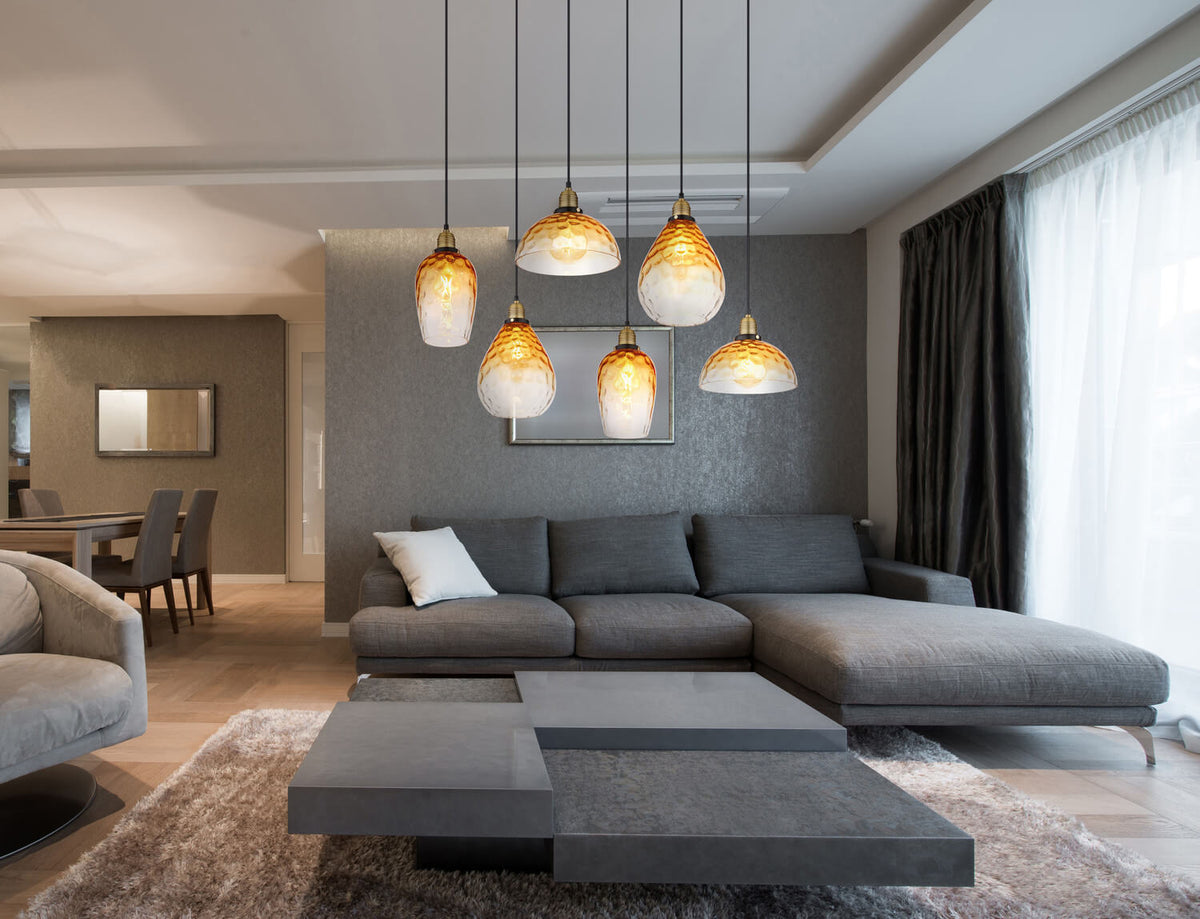 Mise en ambiance dans un salon gris, suspension allumée au-dessus du canapé