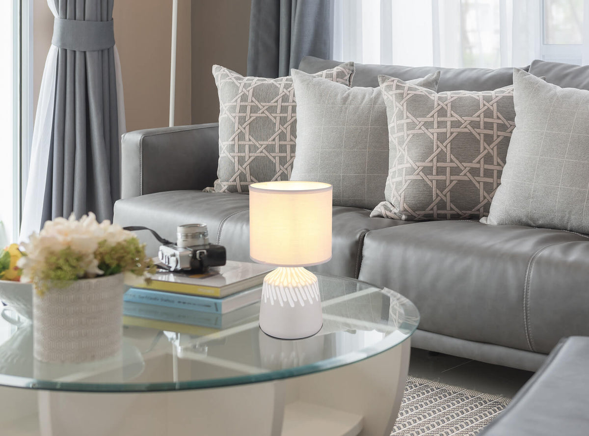 Mise en ambiance de la lampe posée sur une table basse en verre d'un salon