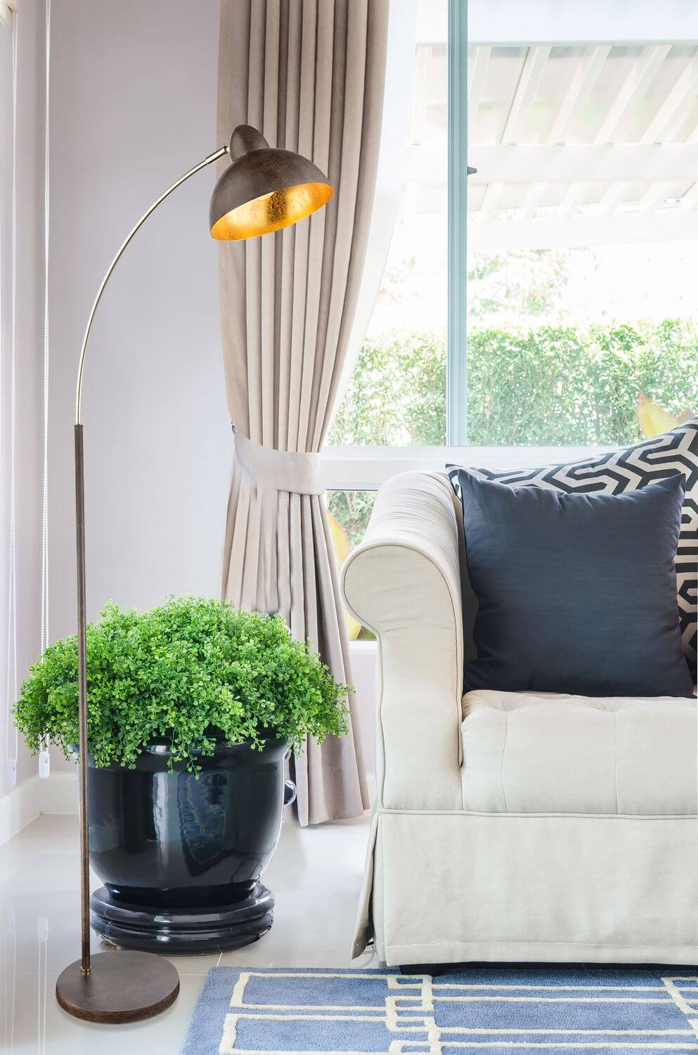 Mise en ambiance du lampadaire dans un salon, près d'un fauteuil, avec rideaux et plante verte