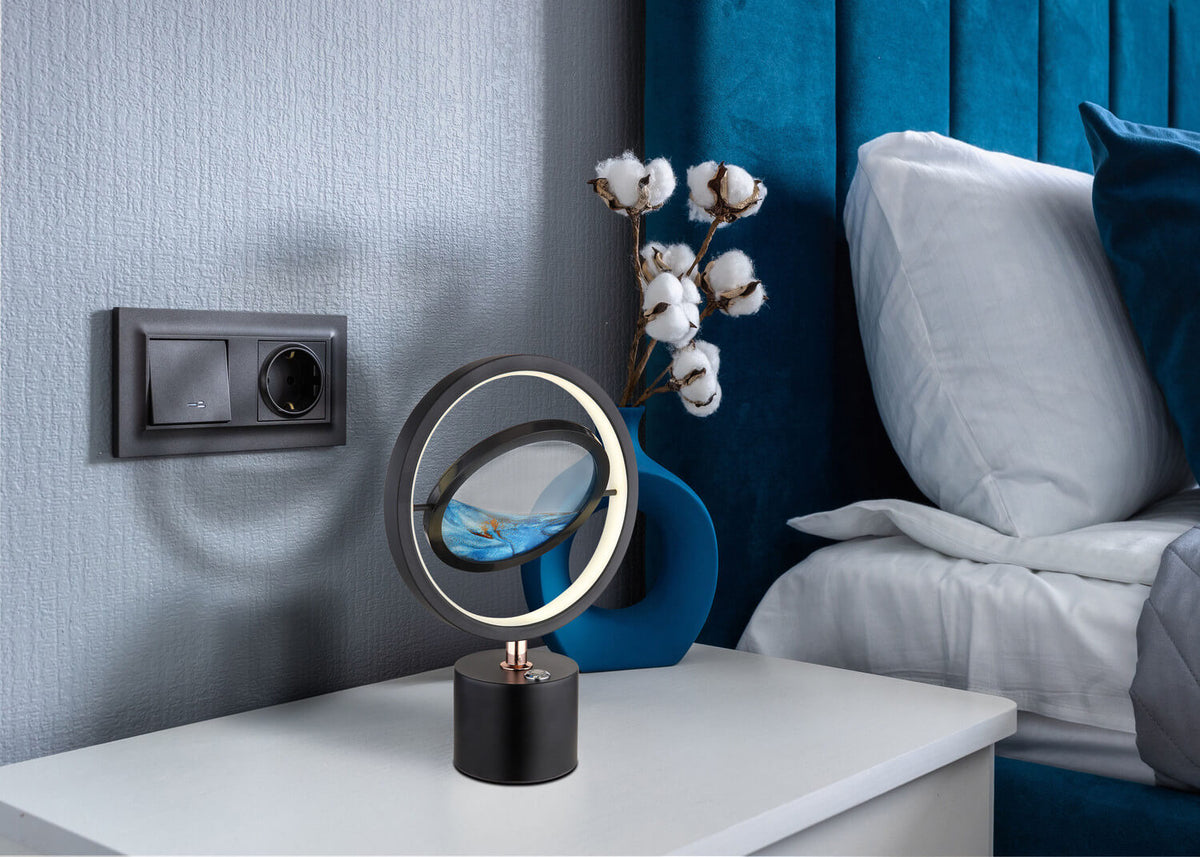 Mise en ambiance sur une table de chevet, lampe allumée près d'un mur bleu.