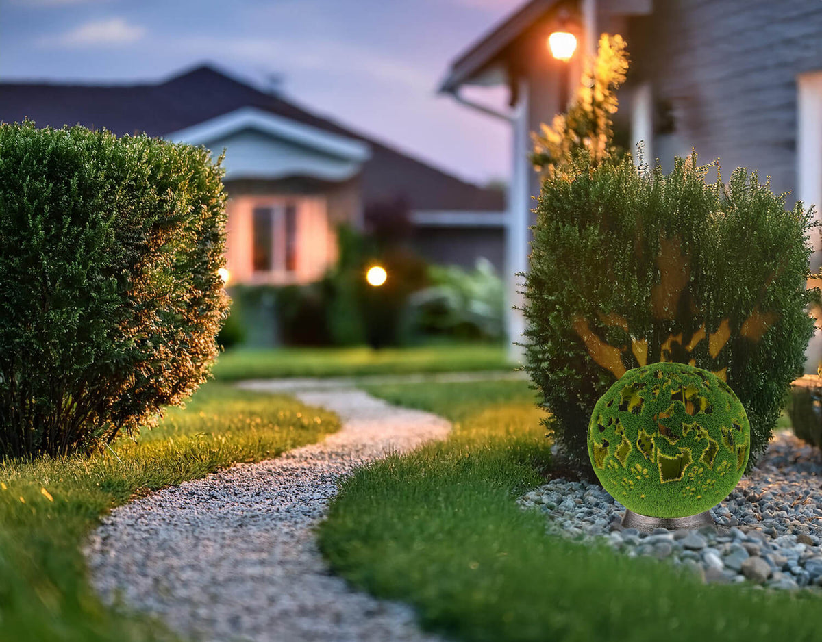 Luminaire décoratif posé sur gravier dans un jardin, allée et maison en arrière-plan