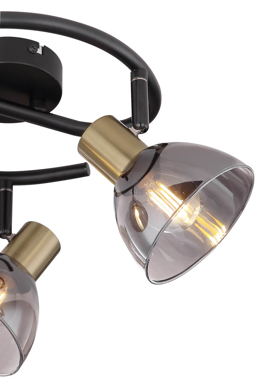 Détail rapproché d'un spot, douille laiton brossé et verre fumé, ampoule filament