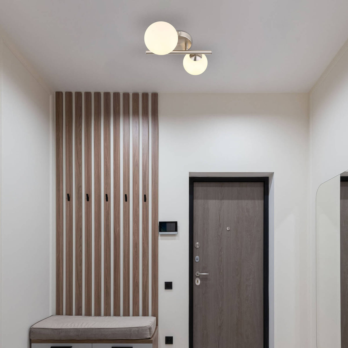 Mise en ambiance dans une entrée moderne, luminaire fixé au plafond au-dessus du banc