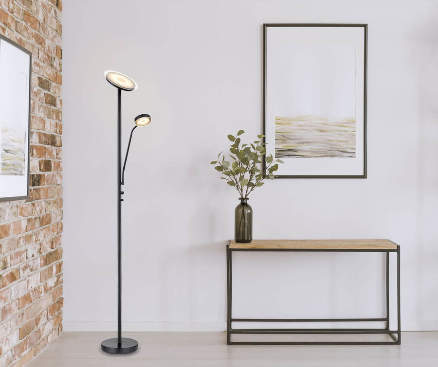 Lampadaire noir mat installé dans un salon devant un mur blanc et une console en bois