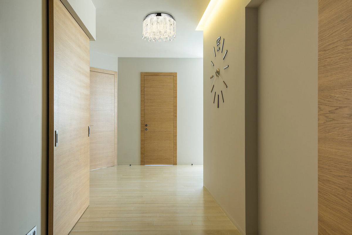 Mise en ambiance du plafonnier allumé dans un couloir aux portes en bois clair