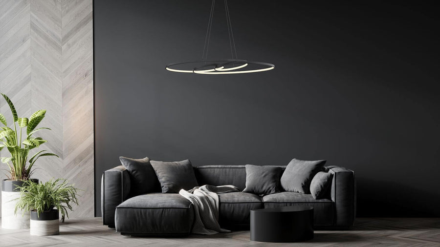 Suspension allumée au-dessus d'un canapé gris dans un salon moderne sombre.