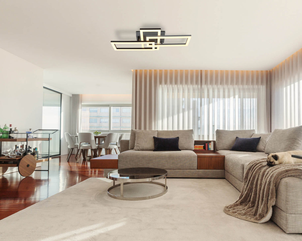 Mise en ambiance dans un salon moderne avec canapé beige et grandes fenêtres.