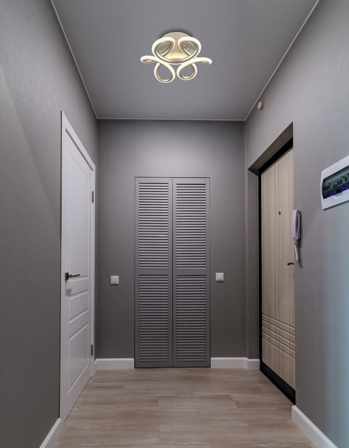 Mise en ambiance dans un couloir gris, plafonnier allumé fixé au plafond.