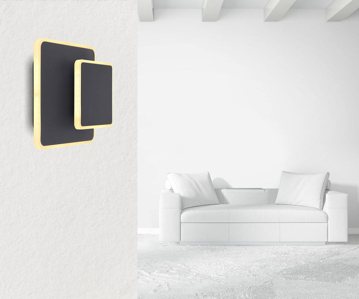 Mise en ambiance dans un salon blanc, applique murale noire et dorée fixée au mur.