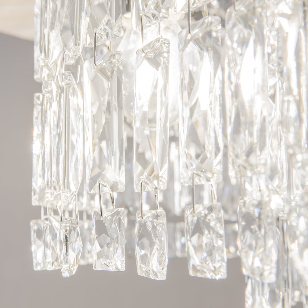 Gros plan sur les prismes de cristal rectangulaires, facettes taillées et attaches métalliques fines suspendues.