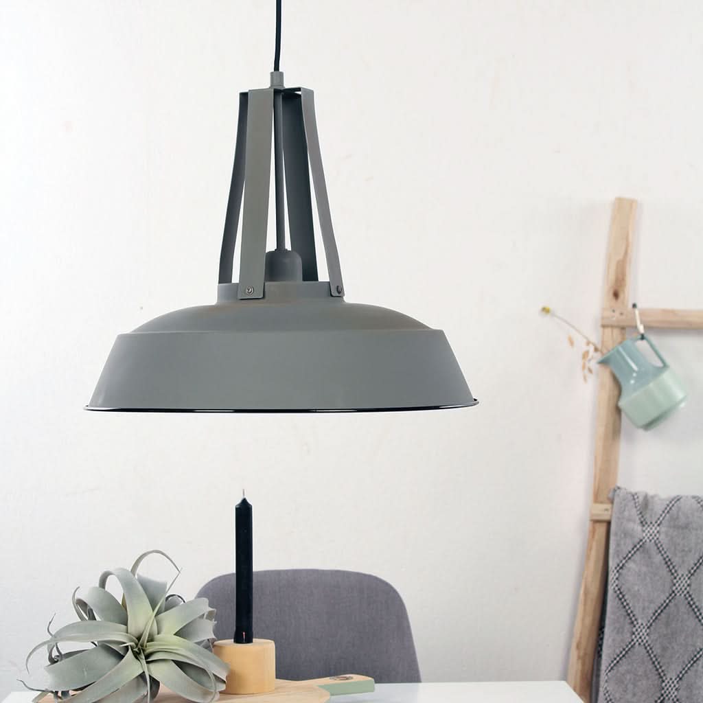 Mise en ambiance au-dessus d'une table avec suspension grise allumée et décor.