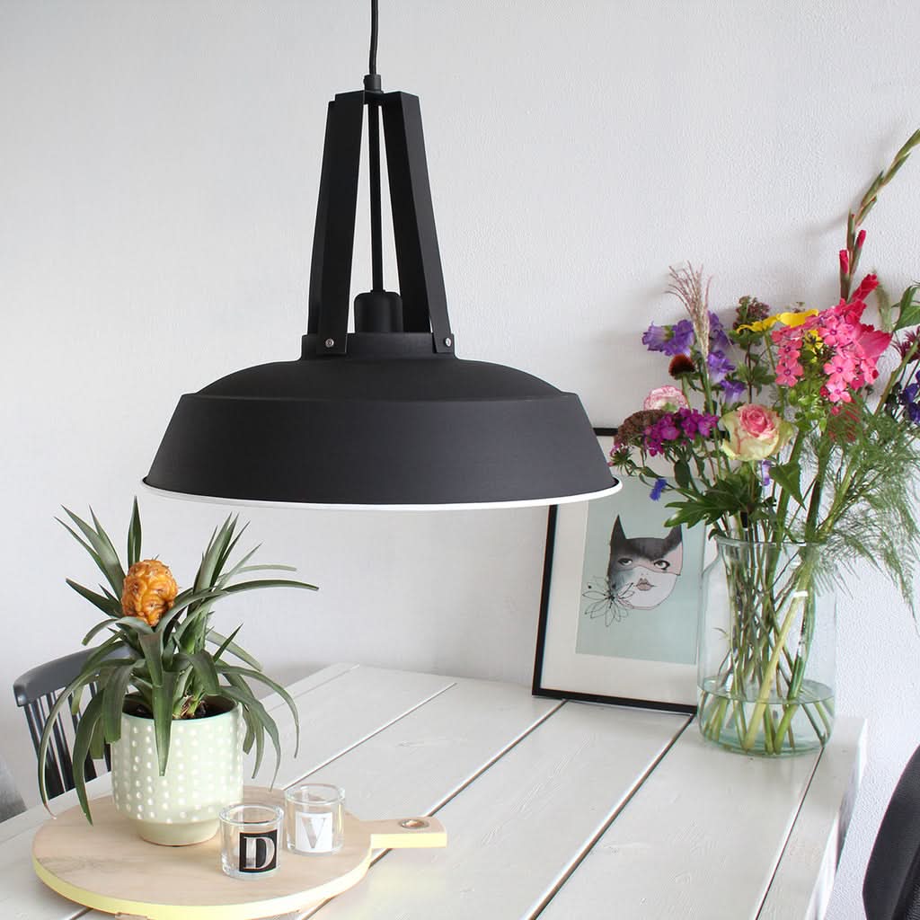 Mise en ambiance au-dessus d'une table blanche avec plantes, vase et cadre.