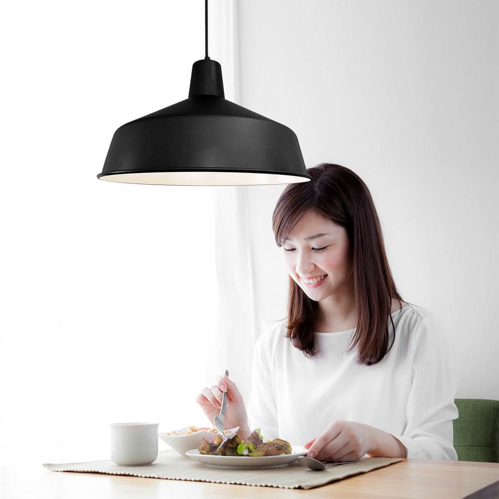 Mise en ambiance au-dessus d'une table, femme souriante dégustant un repas.