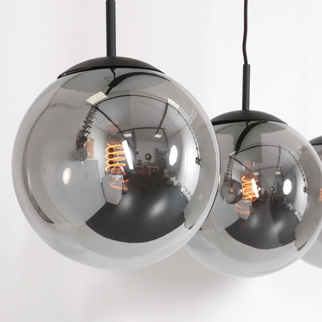 Gros plan sur deux globes en verre fumé montrant leurs reflets et douilles apparentes.