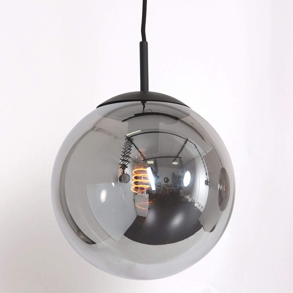 Détail d'un globe en verre fumé suspendu, révélant l'ampoule et les reflets intérieurs.