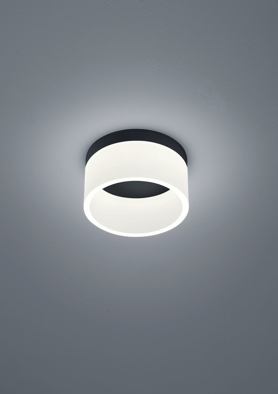 Vue rapprochée du plafonnier cylindrique noir et blanc, éclairé par en dessous.