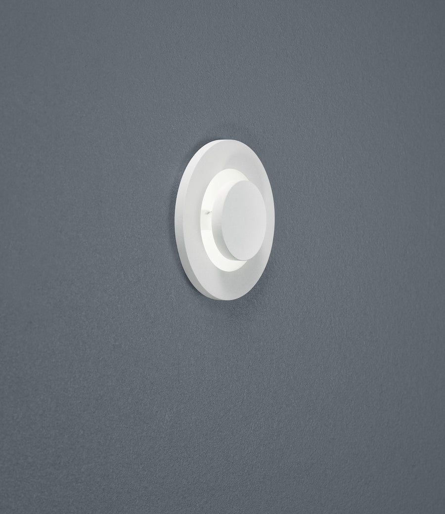Spot encastré blanc vu de face, monté sur un mur gris texturé, cadre circulaire