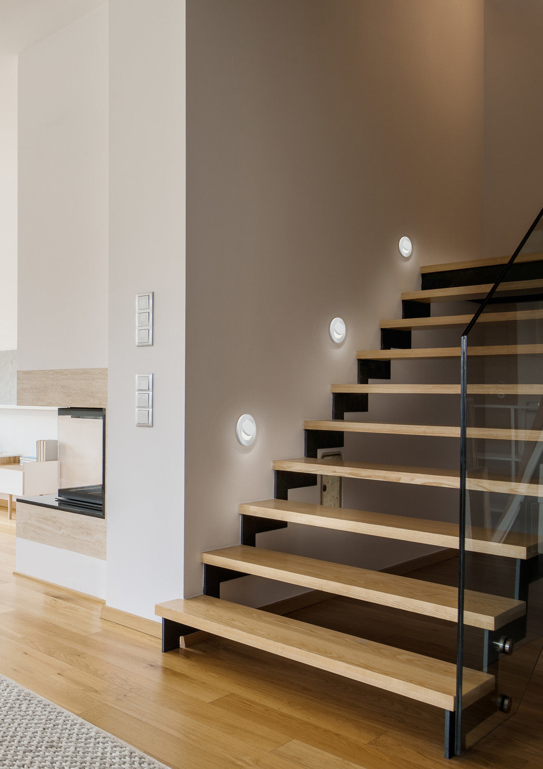 Mise en ambiance dans un escalier : trois spots blancs éclairent les marches en bois