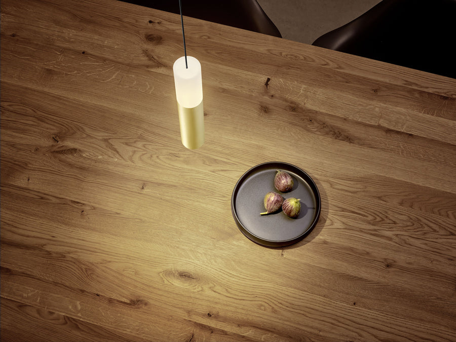 Suspension cylindrique éclairée au-dessus d'une table en bois avec figues