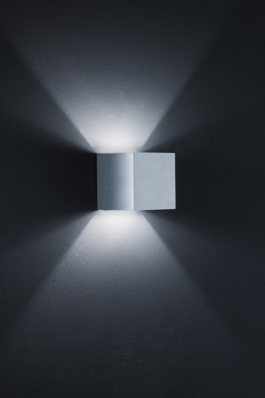 Vue rapprochée du boîtier carré en aluminium brossé fixé sur un mur texturé anthracite