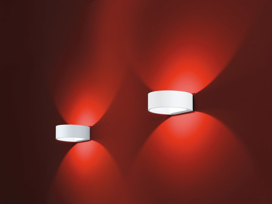 Deux appliques murales cylindriques blanches sur mur rouge, éclairage vers le haut et le bas