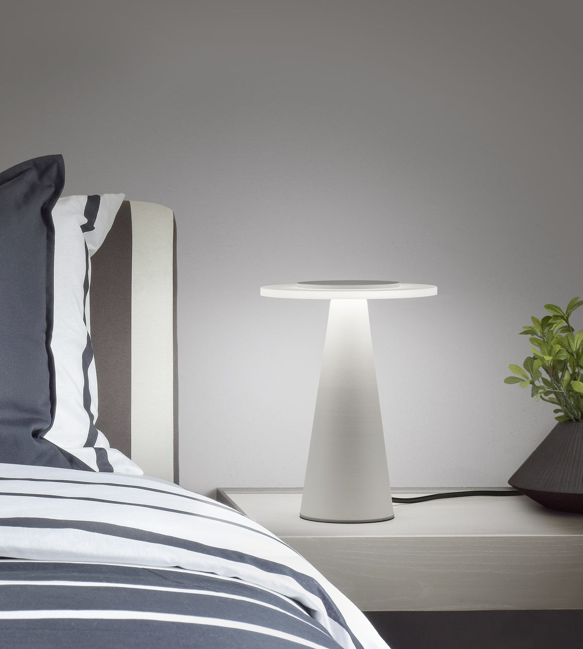 Lampe allumée posée sur une table de chevet près d'un lit