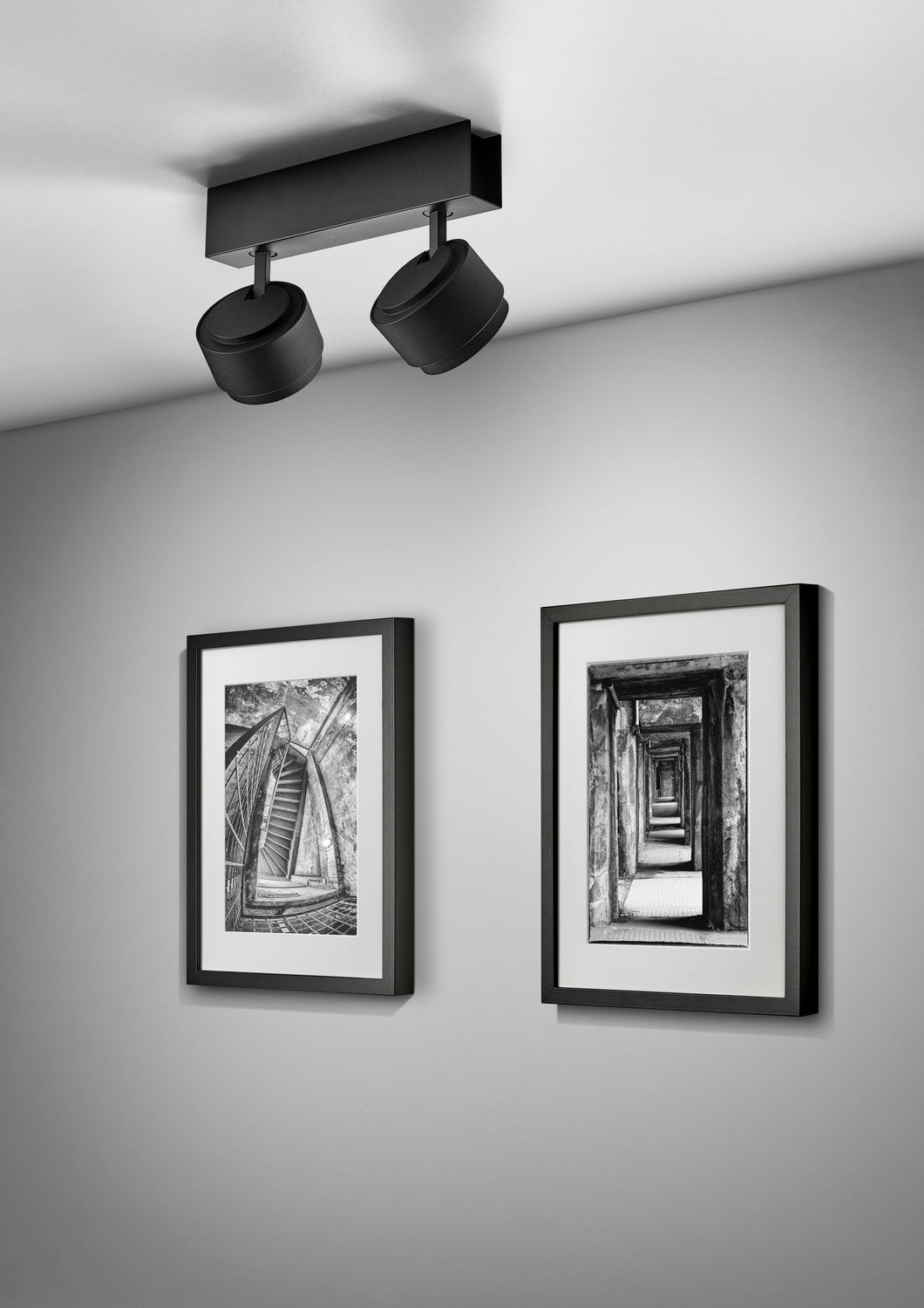 Version noire du plafonnier éclairant deux cadres photo accrochés au mur