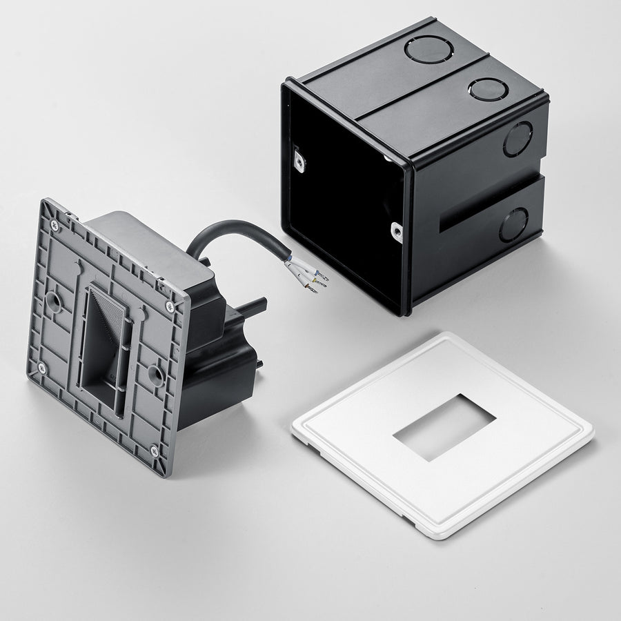 Éclaté du luminaire : boîtier noir, module câblé et plaque de finition blanche