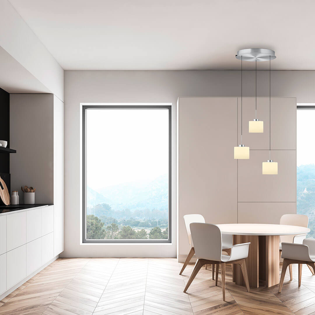 Mise en ambiance du luminaire au-dessus d'une table ronde dans une cuisine lumineuse.