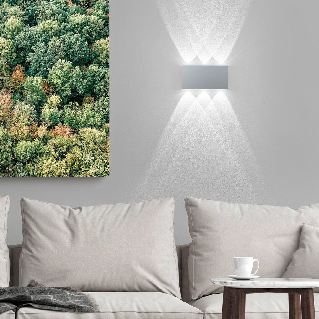 Mise en ambiance : applique murale éclairant un mur au-dessus d'un canapé, lumière haut et bas