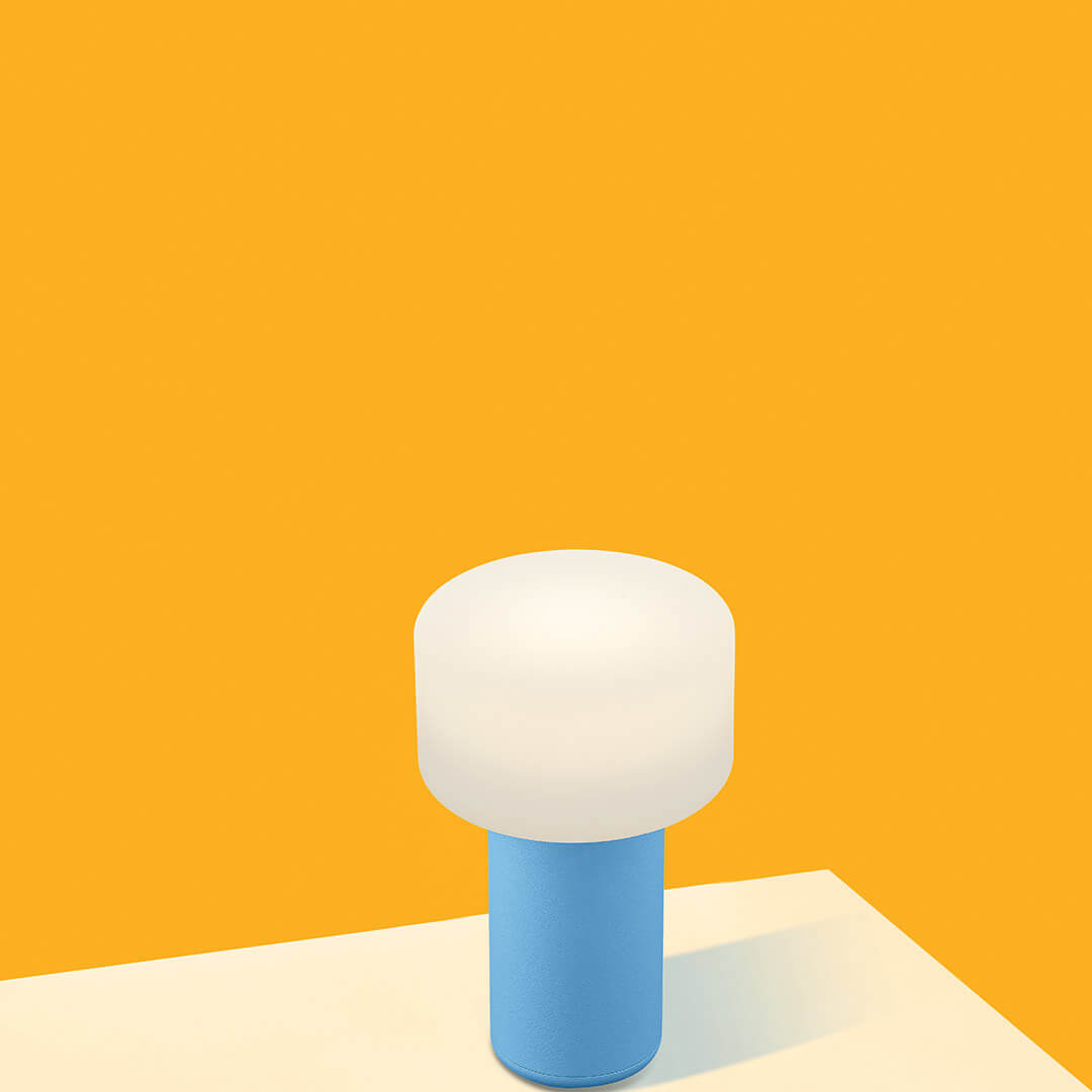Lampe sans fil bleue et blanche posée sur une table, fond jaune vif