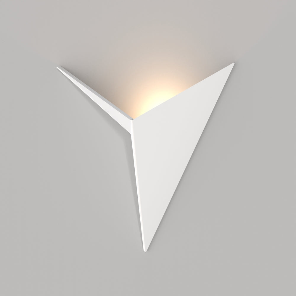 Applique triangulaire blanche allumée sur mur gris, halo lumineux diffus