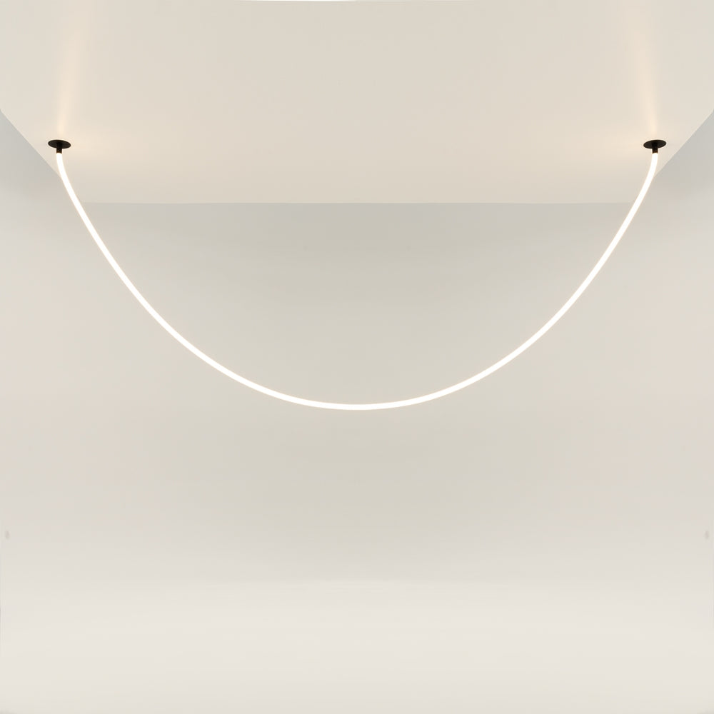 Luminaire fixé au plafond, grande courbe lumineuse devant un mur clair